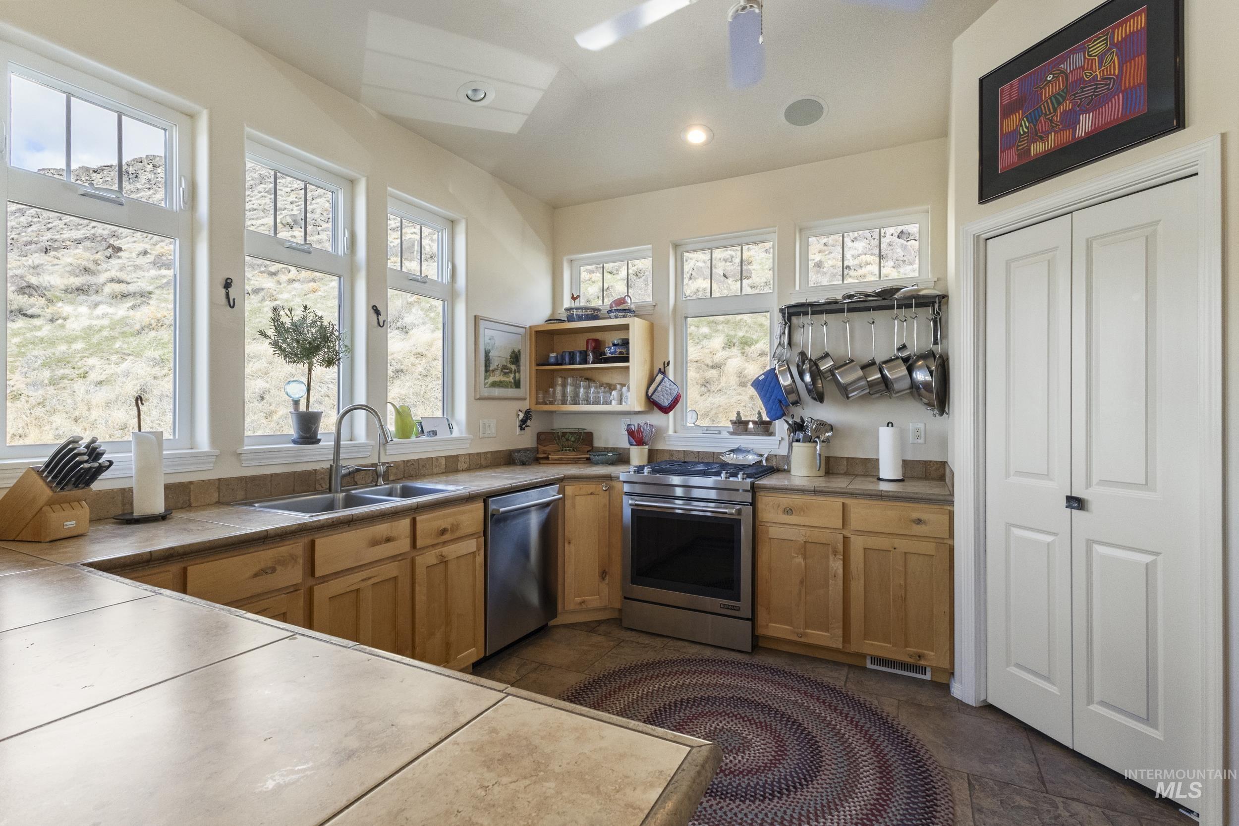 382 River Road Bliss, ID 83314 - Photo 7 of 46 Kitchen with stainless steel appliances, open shelves, tile counters, ceiling fan, and wood finish cabinetry