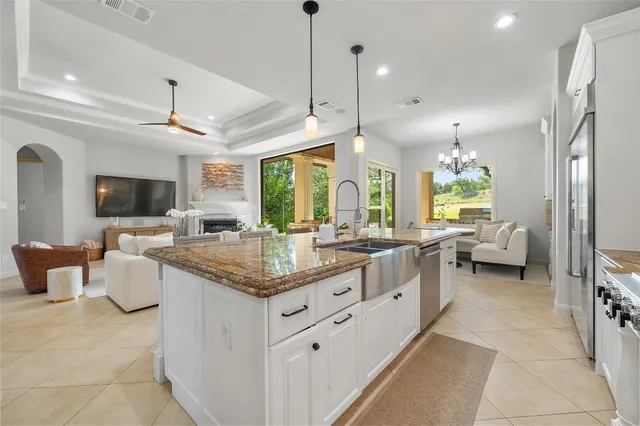 a kitchen with stainless steel appliances granite countertop a stove and a view of living room