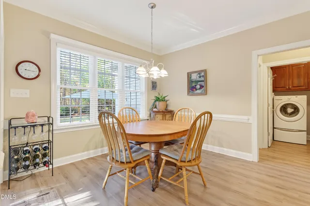 a kitchen with stainless steel appliances granite countertop a refrigerator a sink dishwasher a dining table and chairs with wooden floor