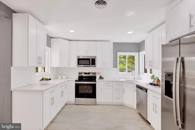 a kitchen with white cabinets and sink