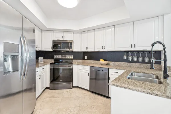 a kitchen with granite countertop a stove sink and refrigerator