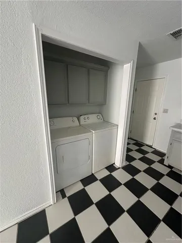 a room with a black white checkered floor and white cabinets