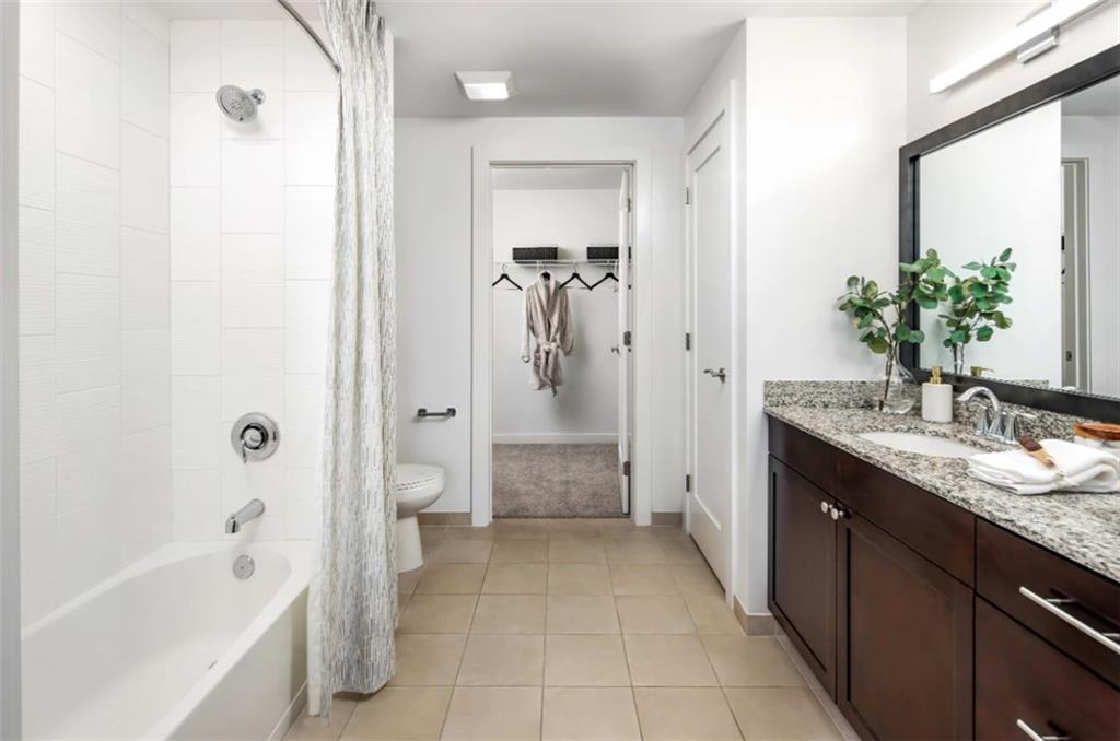 3242 Peachtree Road Northeast, Unit 301 Atlanta, GA 30305 - Photo 19 of 41 a spacious bathroom with a granite countertop sink a mirror a bathtub and a shower