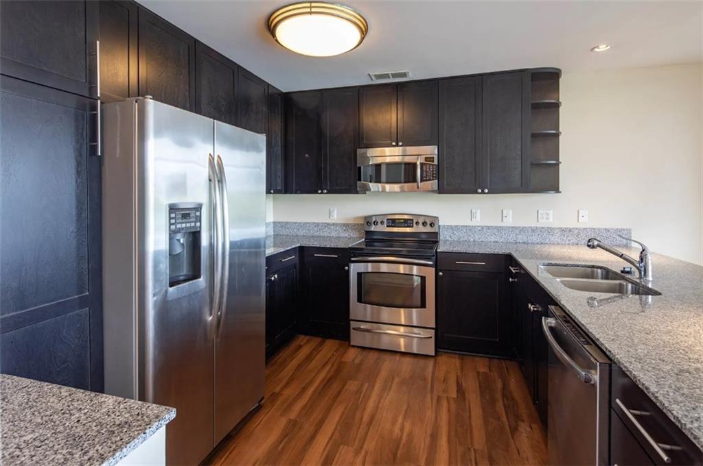 3242 Peachtree Road Northeast, Unit 301 Atlanta, GA 30305 - Photo 6 of 41 a kitchen with kitchen island granite countertop stainless steel appliances and wooden cabinets