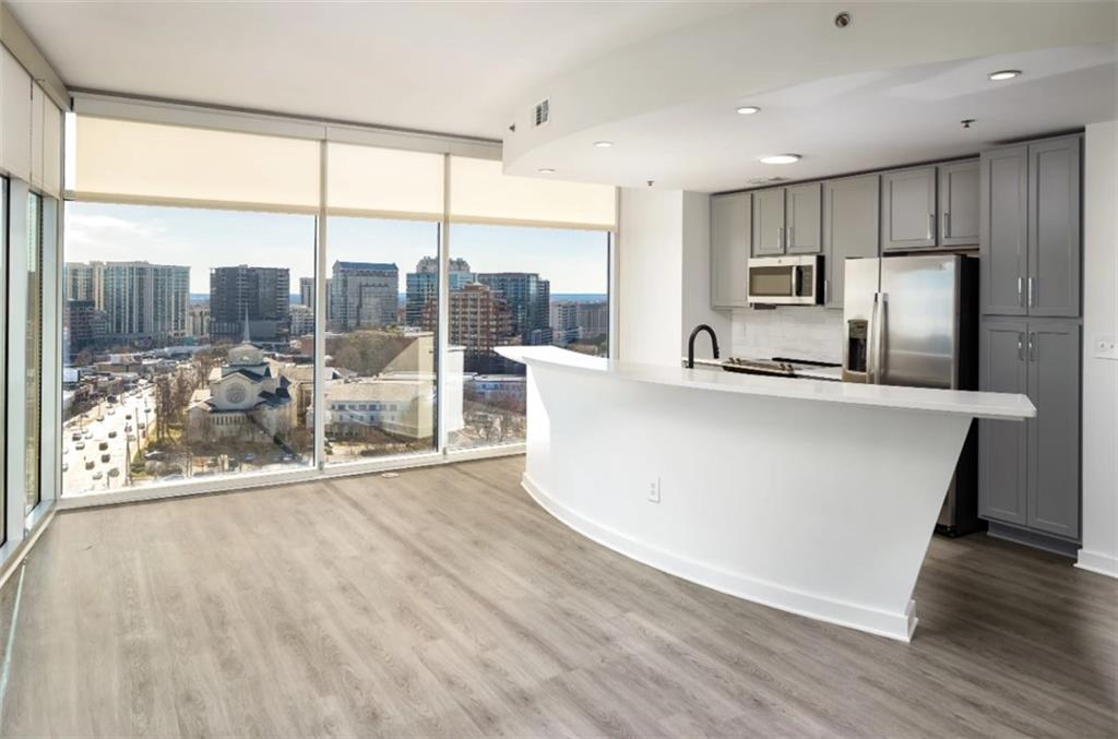 3242 Peachtree Road Northeast, Unit 301 Atlanta, GA 30305 - Photo 7 of 41 a large kitchen with kitchen island a large window a sink and a counter top space