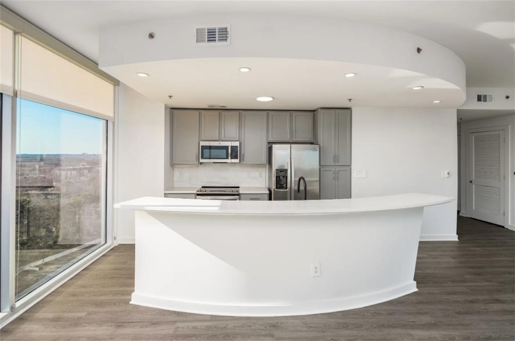 3242 Peachtree Road Northeast, Unit 301 Atlanta, GA 30305 - Photo 9 of 41 a large kitchen with stainless steel appliances a large counter top and a wooden floors