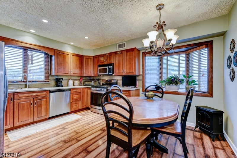 52 Ashburn Road Wayne, NJ 07470 - Photo 17 of 49 a kitchen with stainless steel appliances granite countertop a stove top oven a refrigerator a sink dishwasher a dining table and chairs with wooden floor