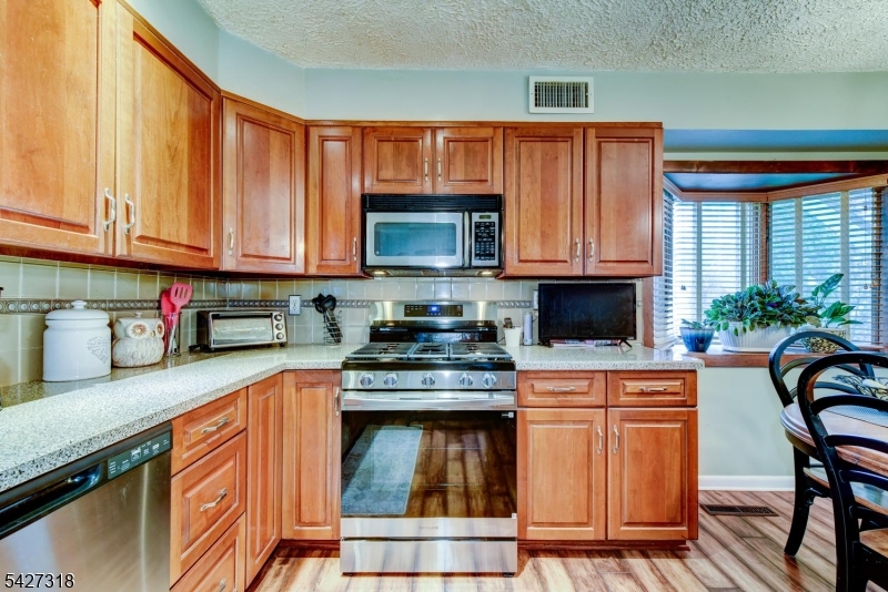 52 Ashburn Road Wayne, NJ 07470 - Photo 20 of 49 a kitchen with granite countertop a stove top oven a sink dishwasher and cabinets with wooden floor