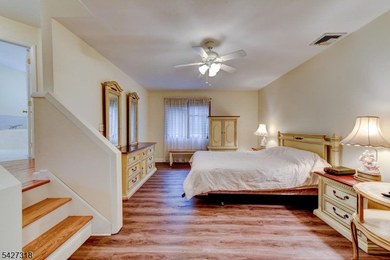 52 Ashburn Road Wayne, NJ 07470 - Photo 38 of 49 a spacious bedroom with a large bed and a chandelier