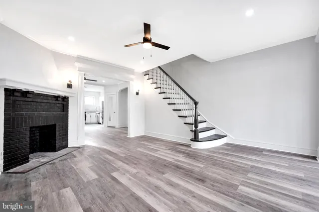 a view of an empty room with wooden floor fireplace and a window