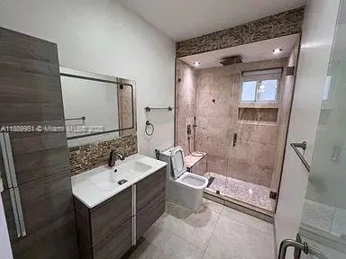 a bathroom with a sink a toilet a mirror and shower