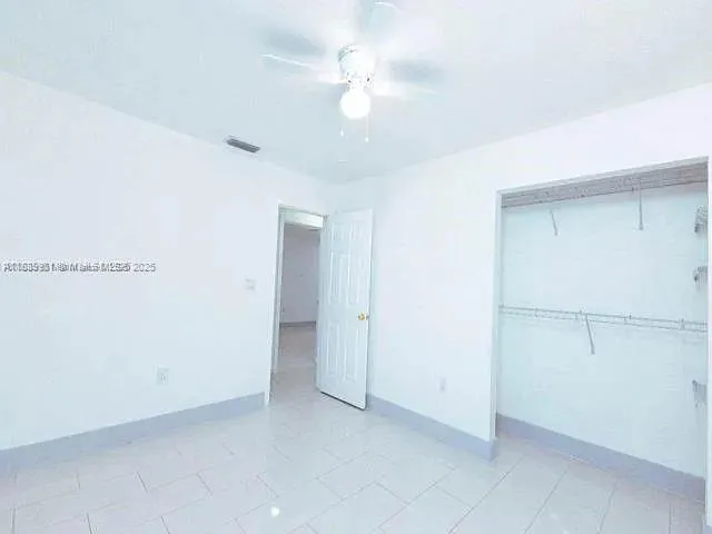 an empty room with a ceiling fan and a window