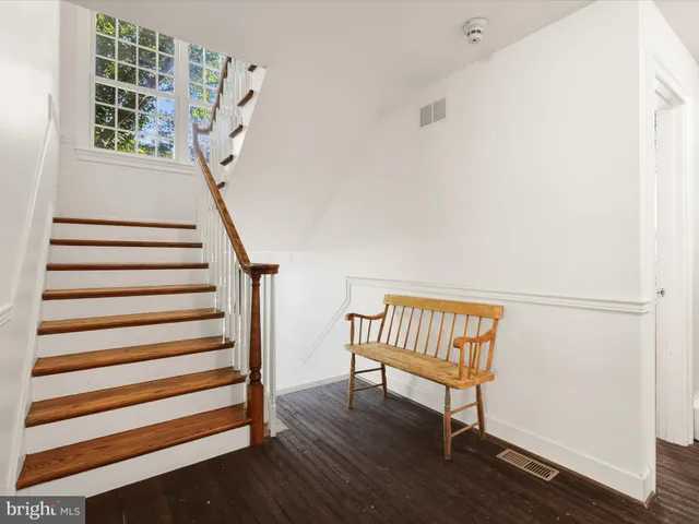a bathroom with a granite countertop toilet a sink a mirror and a window