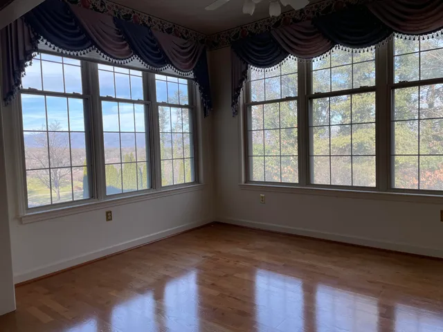 a view of an empty room with a window and wooden floor