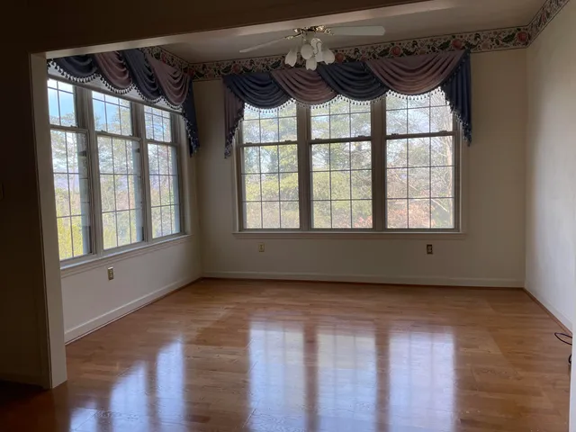 a view of an empty room with a window and a wooden floor