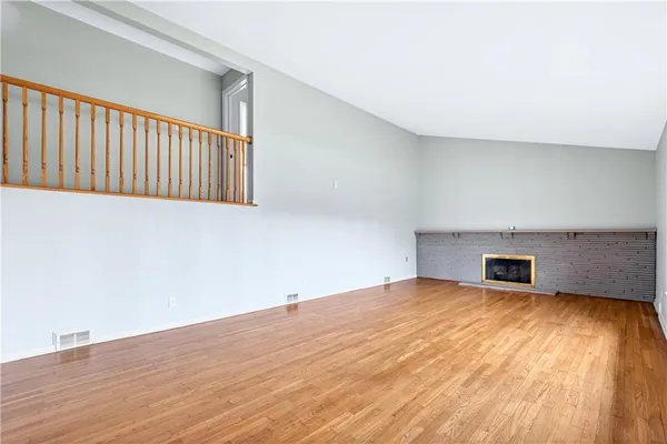 a view of an empty room with wooden floor and windows