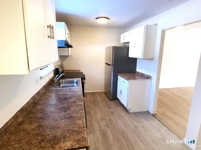 a kitchen with stainless steel appliances a refrigerator and wooden floor