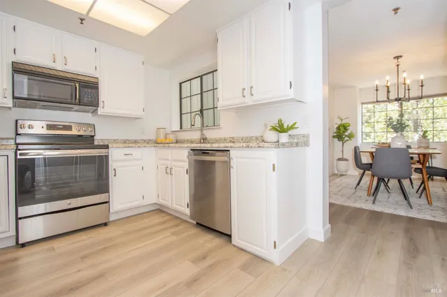 a kitchen with a stove a sink and white cabinets