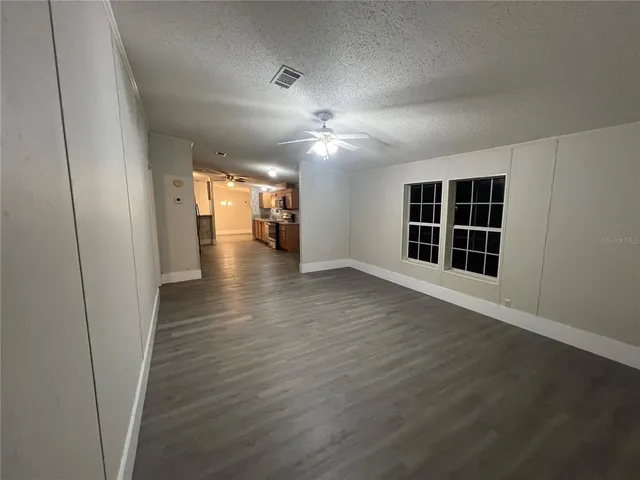 a view of an empty room with wooden floor and windows