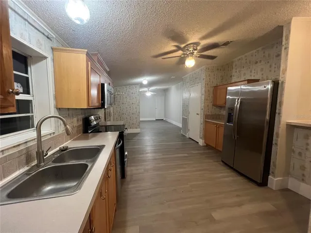 a kitchen with stainless steel appliances kitchen island granite countertop a refrigerator and a stove top oven