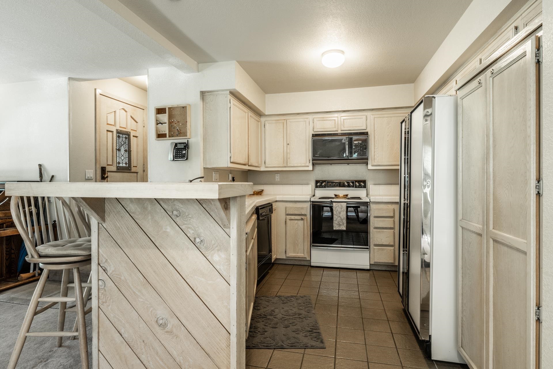 609 Golden Creek Road, Unit 609 Mammoth Lakes, CA 93546 - Photo 27 of 42 Kitchen featuring wood-finish cabinetry, built-in microwave, and tile flooring