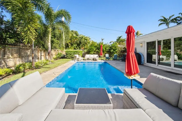 a view of a backyard with swimming pool and sitting area