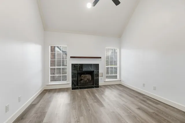 an empty room with windows and fireplace