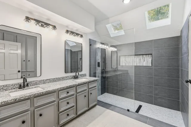 a bathroom with a granite countertop sink mirror and shower