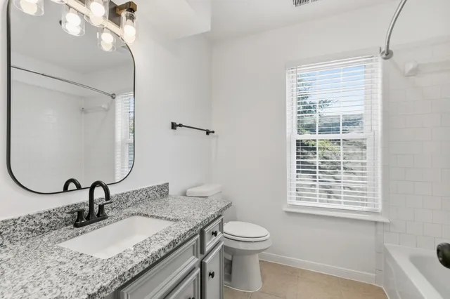 a bathroom with a granite countertop sink a toilet and a mirror