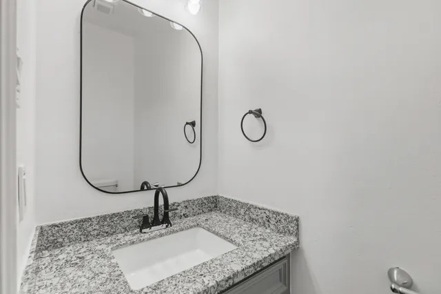a bathroom with a granite countertop sink and a mirror