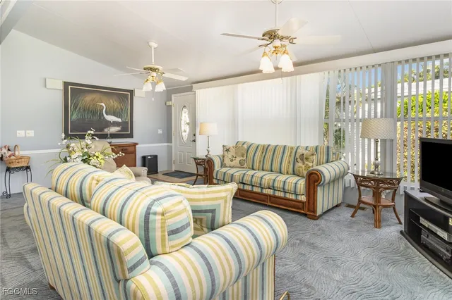 a living room with furniture flat screen tv and a large window