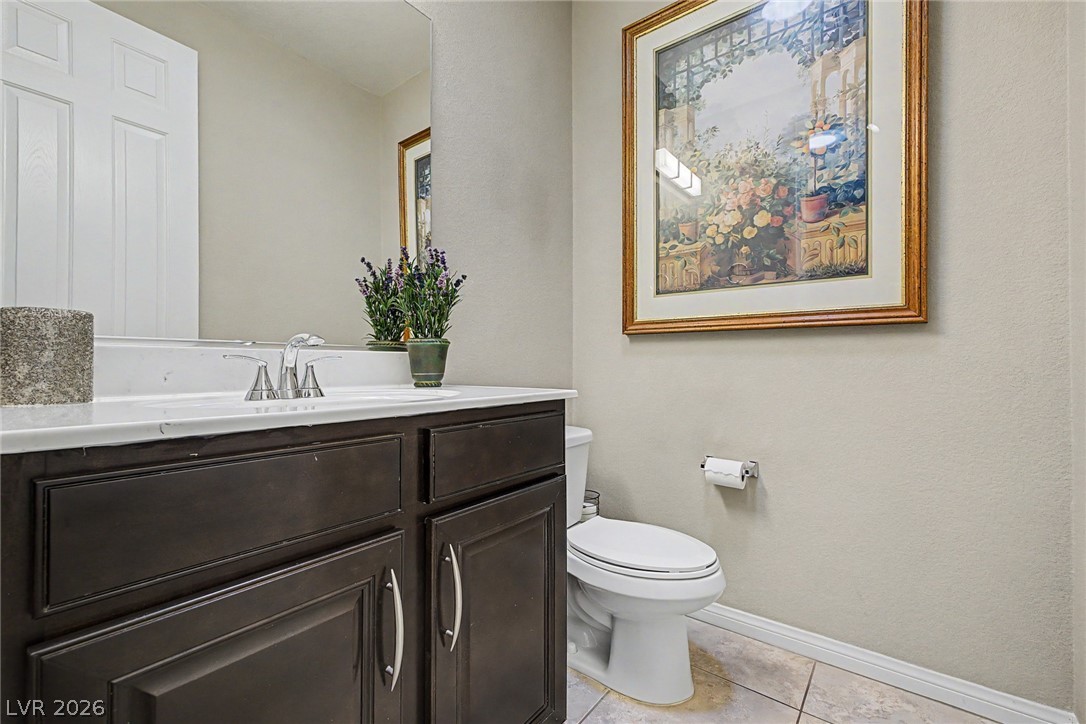 7415 Campbell Ranch Avenue Las Vegas, NV 89179 - Photo 25 of 52 A well-appointed powder room features a dark wood vanity with a pristine white countertop.