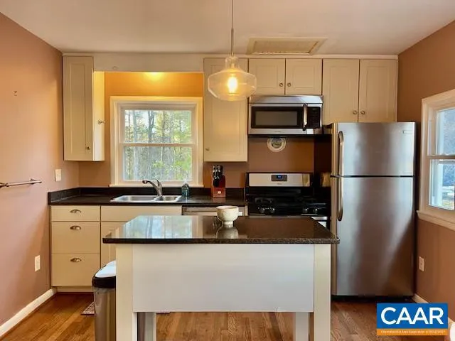 a kitchen with stainless steel appliances granite countertop a refrigerator a stove a sink and a microwave