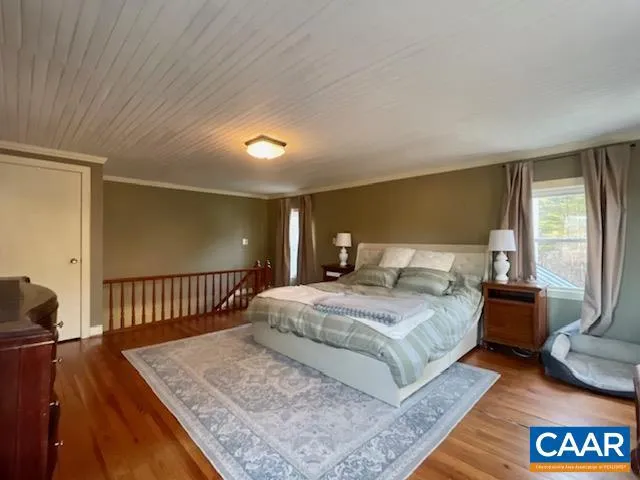 a spacious bedroom with a bed a couch and a window with wooden floor