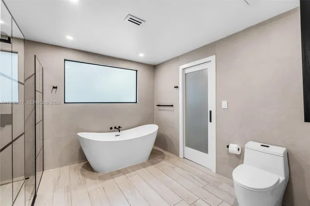 a spacious bedroom with a bed and wooden floor