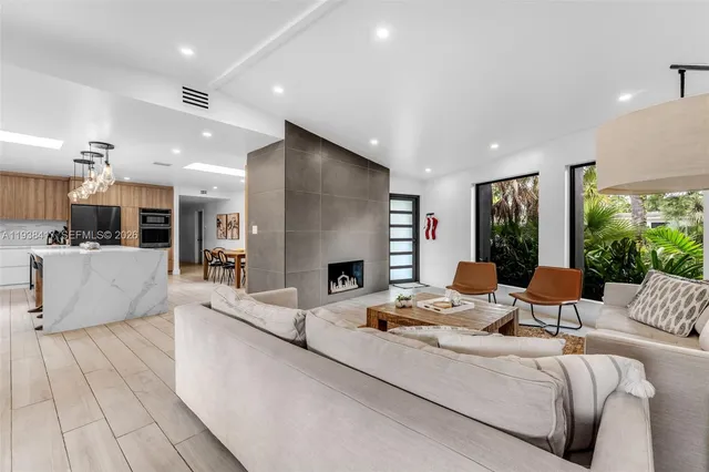 a large living room with stainless steel appliances furniture wooden floor and a large window