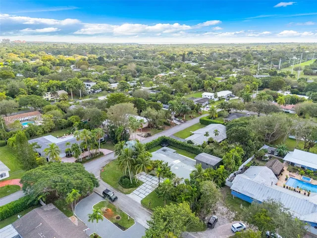 an aerial view of residential houses with outdoor space and trees