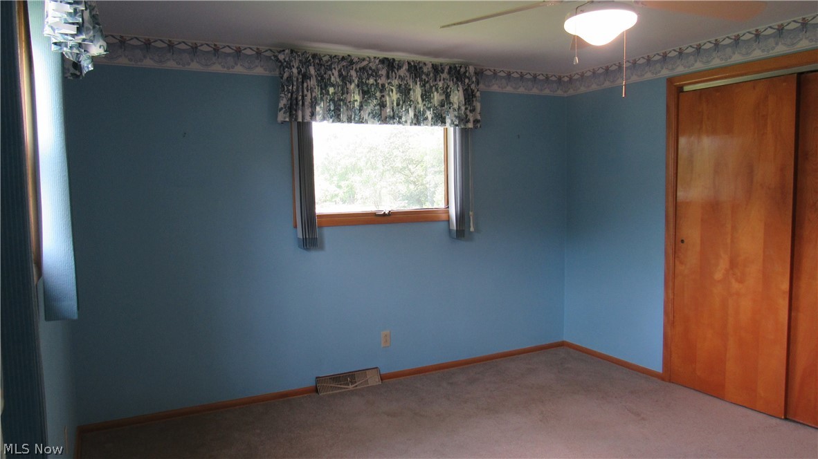 6841 Navarre Road Southwest Massillon, OH 44646 - Photo 24 of 50 Carpeted room featuring a window, built-in closet with wood-finish sliding closet doors, and a ceiling fan with integrated lighting