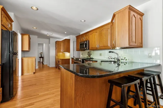 a kitchen with stainless steel appliances granite countertop a stove top oven a sink dishwasher a dining table and chairs with wooden floor