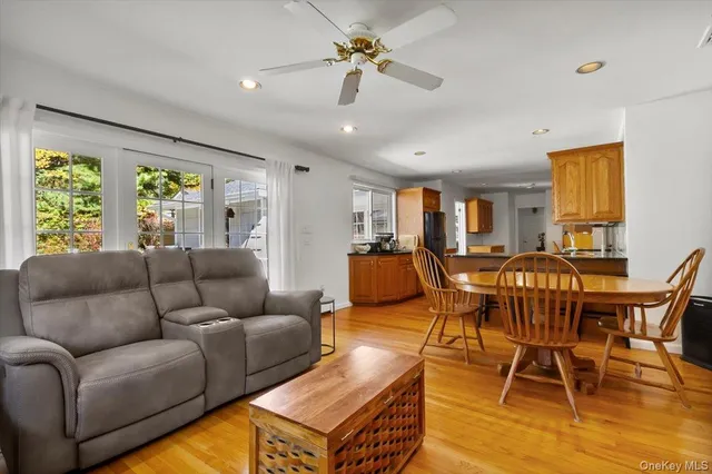 a living room with furniture a ceiling fan and a large window