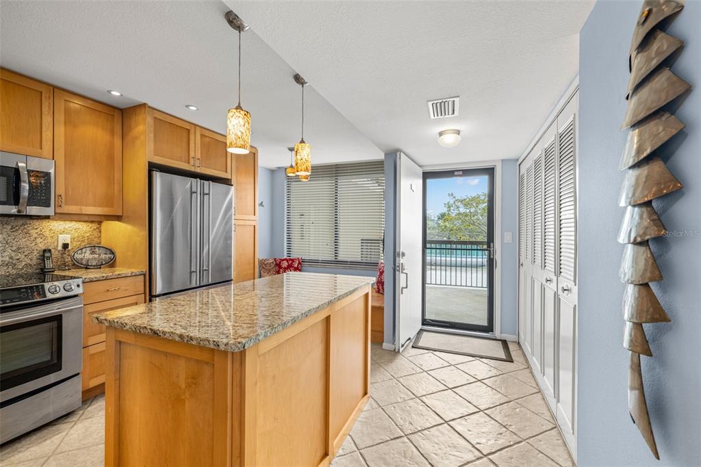 9495 Blind Pass Road, Unit 204 St. Pete Beach, FL 33706 - Photo 12 of 36 a kitchen with stainless steel appliances granite countertop a sink and a refrigerator
