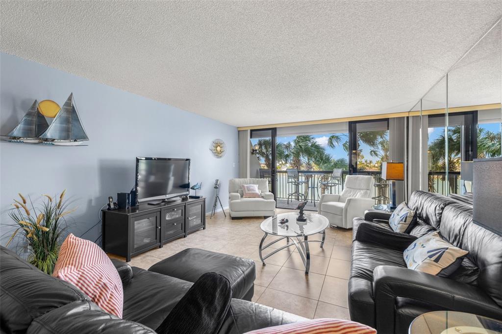9495 Blind Pass Road, Unit 204 St. Pete Beach, FL 33706 - Photo 13 of 36 a living room with furniture and a flat screen tv