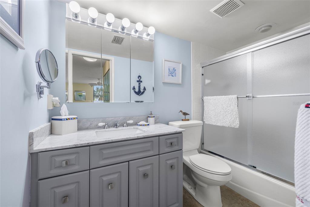 9495 Blind Pass Road, Unit 204 St. Pete Beach, FL 33706 - Photo 19 of 36 a bathroom with a granite countertop sink mirror toilet and shower