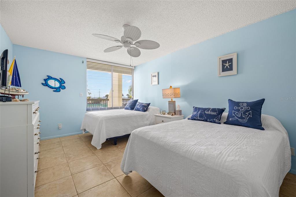 9495 Blind Pass Road, Unit 204 St. Pete Beach, FL 33706 - Photo 20 of 36 a bedroom with a bed and a chandelier