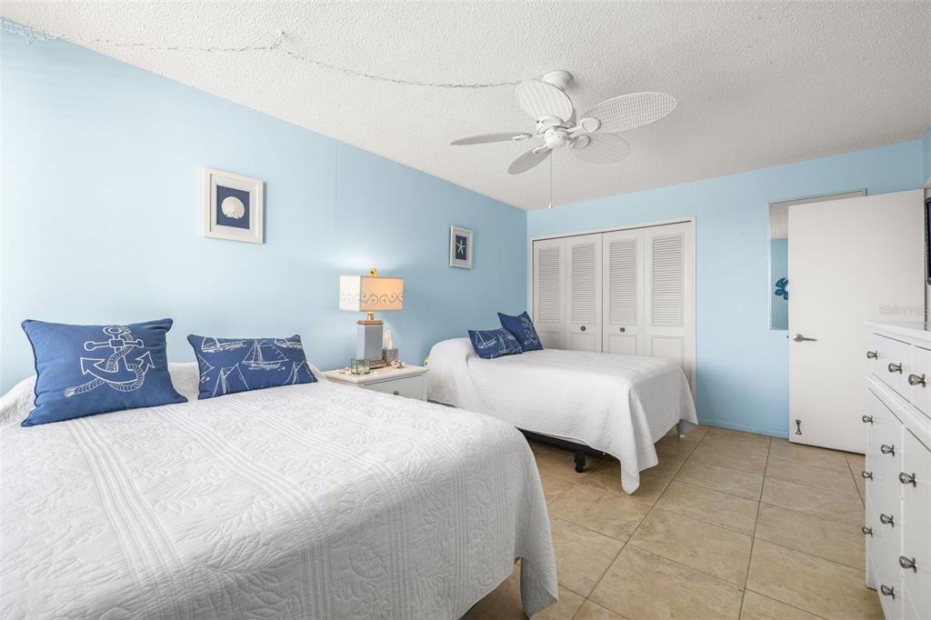 9495 Blind Pass Road, Unit 204 St. Pete Beach, FL 33706 - Photo 21 of 36 a bedroom with two separate beds and painting on the wall