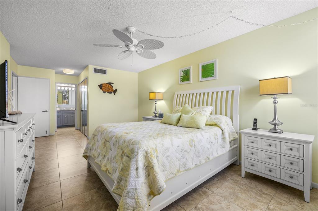 9495 Blind Pass Road, Unit 204 St. Pete Beach, FL 33706 - Photo 5 of 36 a bedroom with a bed and a flat tv screen on dresser