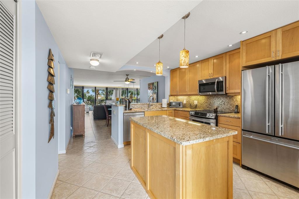 9495 Blind Pass Road, Unit 204 St. Pete Beach, FL 33706 - Photo 7 of 36 a kitchen with stainless steel appliances granite countertop a refrigerator a sink a stove top oven a counter space and cabinets