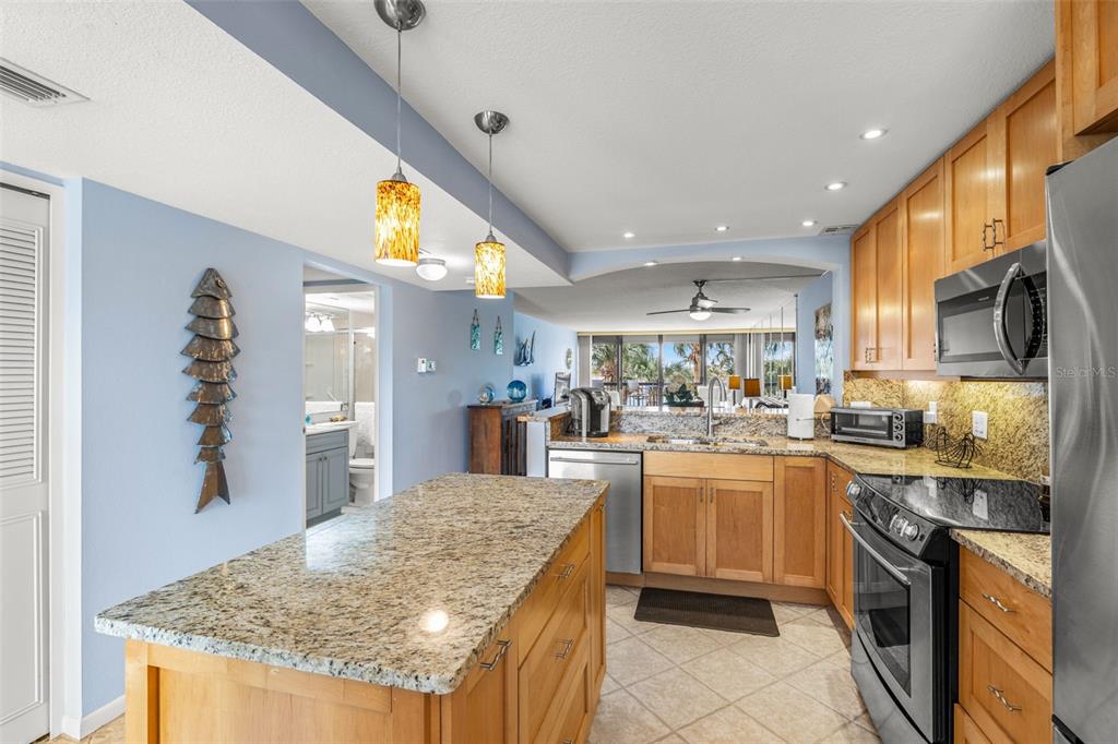 9495 Blind Pass Road, Unit 204 St. Pete Beach, FL 33706 - Photo 8 of 36 a kitchen with stainless steel appliances granite countertop a sink stove and refrigerator