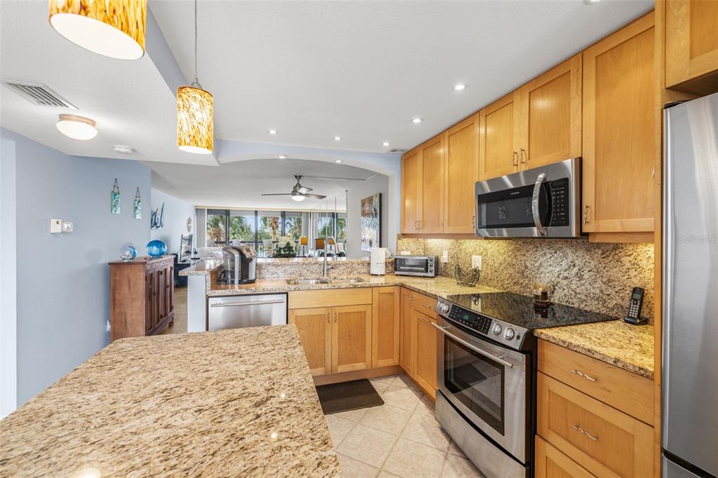 9495 Blind Pass Road, Unit 204 St. Pete Beach, FL 33706 - Photo 9 of 36 a kitchen with stainless steel appliances granite countertop a sink stove and refrigerator