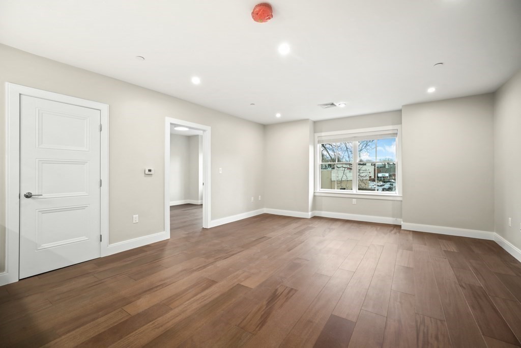 425 Lagrange Street, Unit 109 Boston, MA 02132 - Photo 26 of 42 an empty room with wooden floor and window